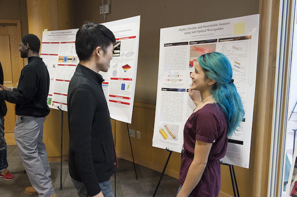 Two students discuss research at a poster.