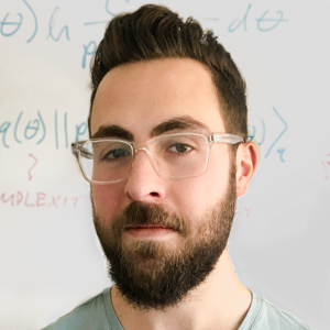 Headshot of Alex Lavin in front of whiteboard with math problems