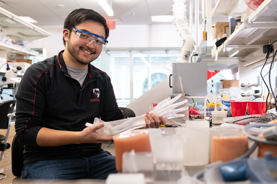 Miguel Martinez in the lab holding a model of a human arm.