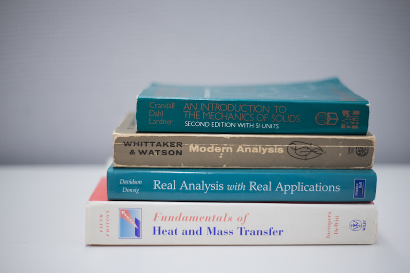 Stack of textbooks: An introduction to the mechanics of solids, Modern Analysis, Real Analysis with Real Applications, Fundamentals of Heat and Mass Transfer